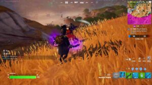 Fortnite how to slide kick: A player sliding towards to players on a hill covered in yellow grass.