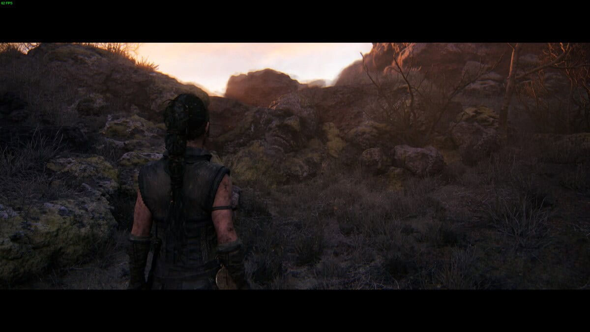 Hellblade 2 Hidden Faces locations: Senua stands facing rocky terrain and a glowing horizon in a desolate landscape.