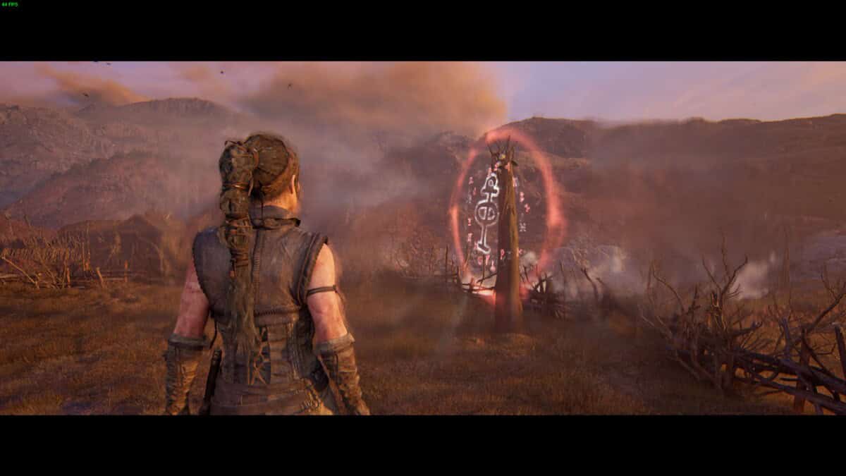 Hellblade 2 Lorestangir locations: Senua standing in the setting sun near a runic totem.