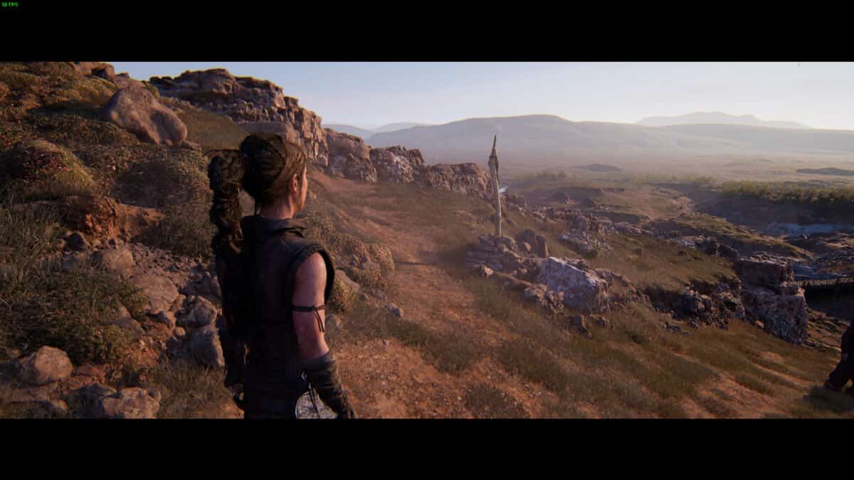 Hellblade 2 Lorestangir locations: Senua overlooking a hill and a marker on the road.