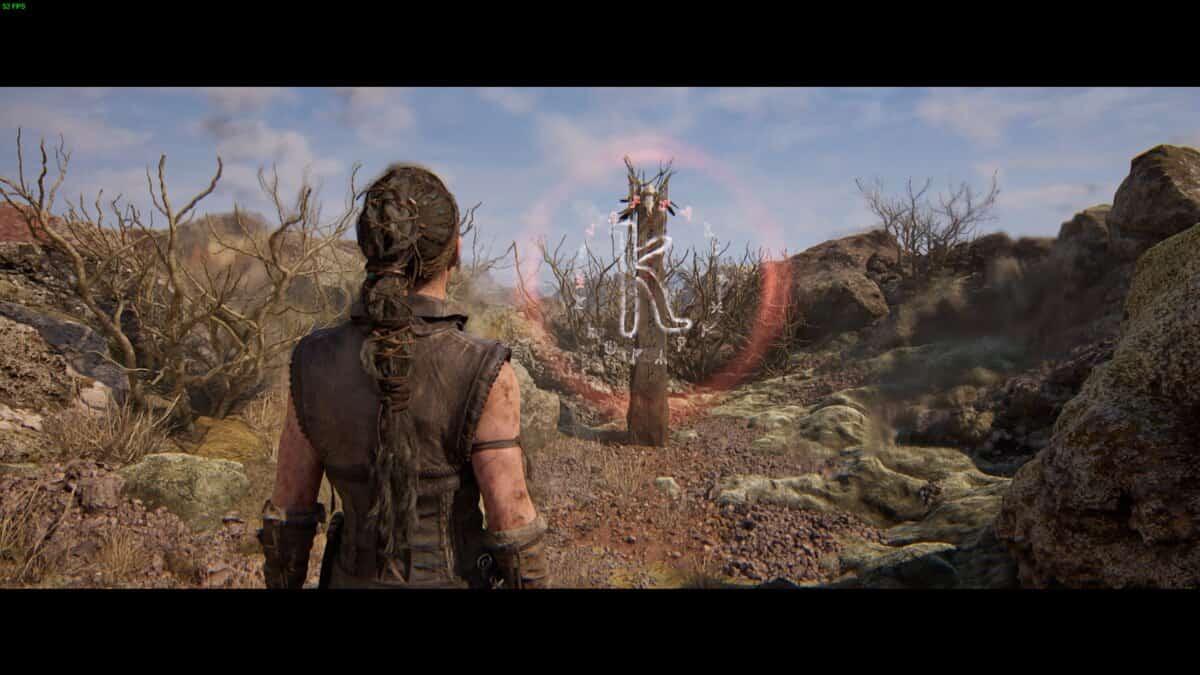 Hellblade 2 Lorestangir locations: Senua stands in a rocky, barren landscape facing a glowing runic totem.