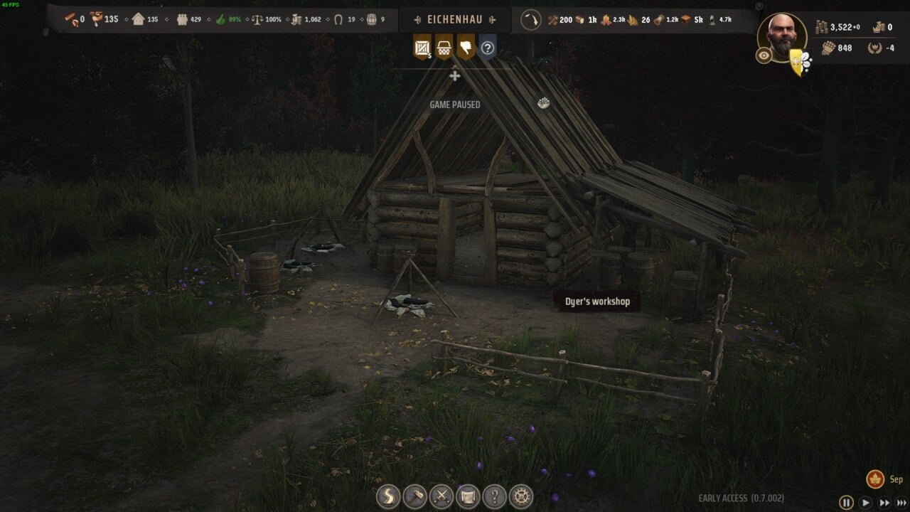 Manor Lords buildings: Screenshot of a video game featuring a rustic dyer's workshop at night with various crafting items and Manor Lords buildings in the background.