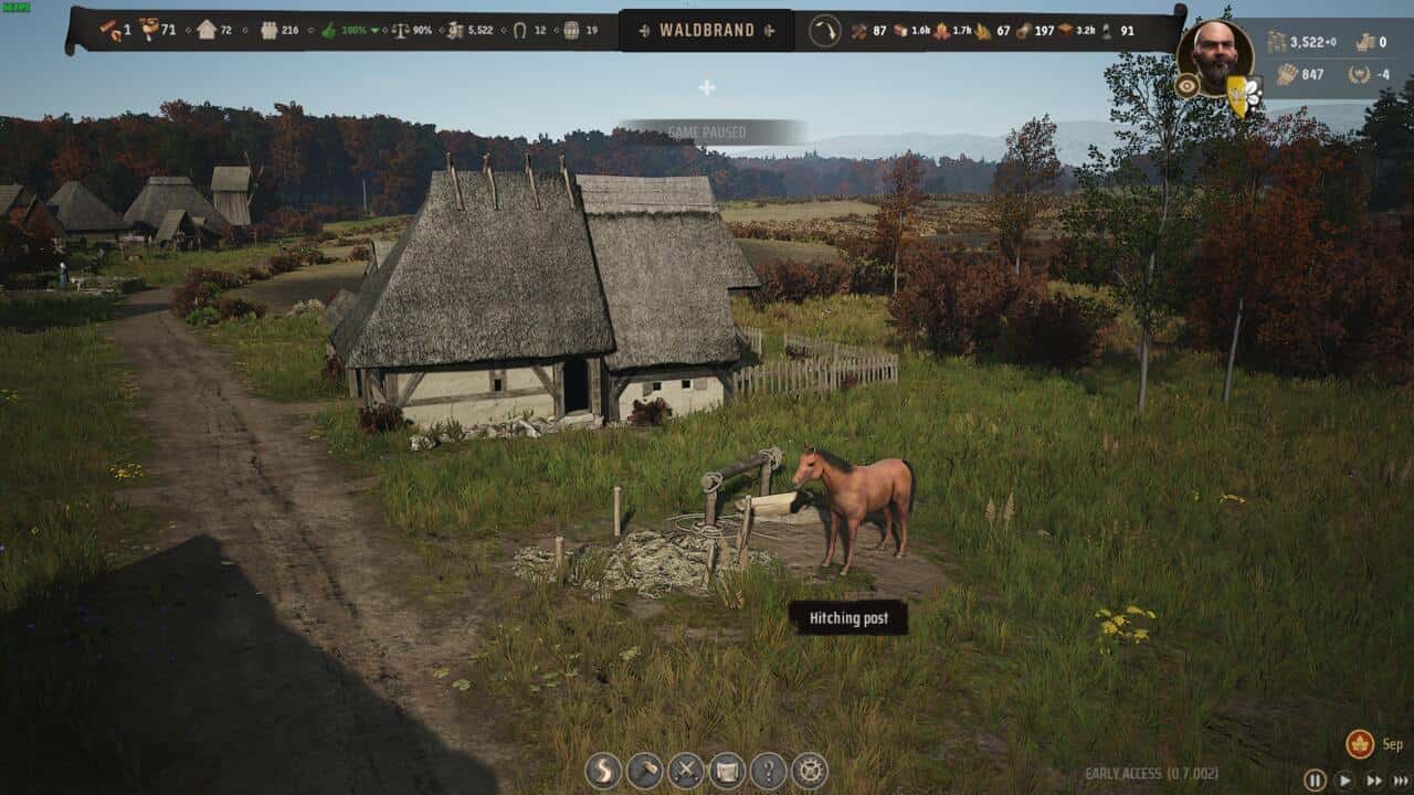 Manor Lords buildings: A screenshot from the medieval-themed video game Manor Lords showing a rural scene with thatched-roof buildings, a horse tethered to a hitching post, and lush greenery.