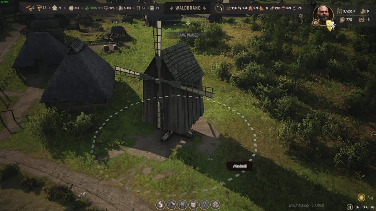 Manor Lords buildings: Screenshot from a village management video game showing a windmill surrounded by trees and Manor Lords buildings, with game interface elements displayed.