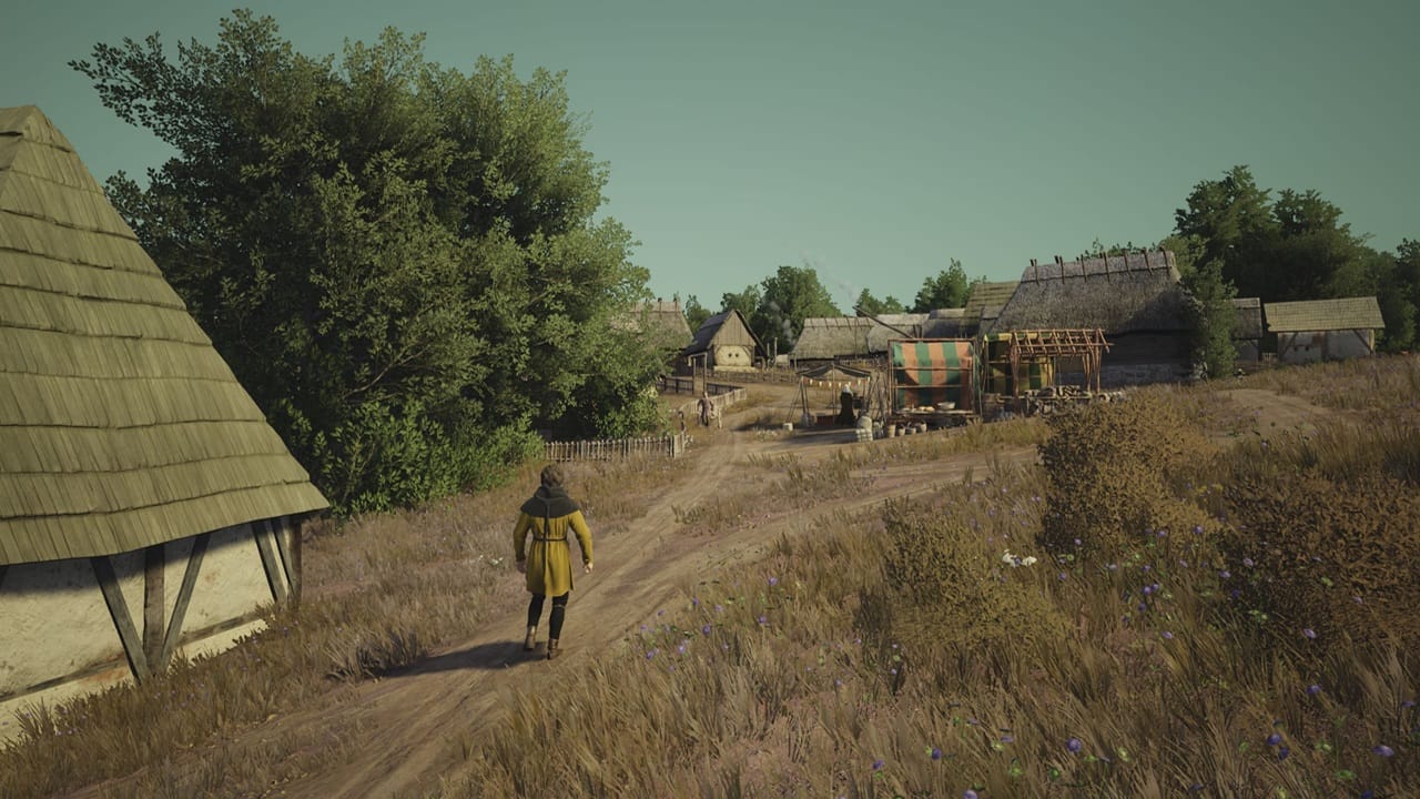 Manor Lords multi-player: A person in a yellow tunic walks toward a medieval village. Image via Slavic Magic.
