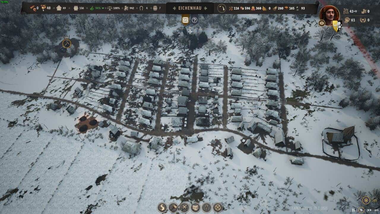 Manor Lords review: aerial view of a medieval village covered in snow.