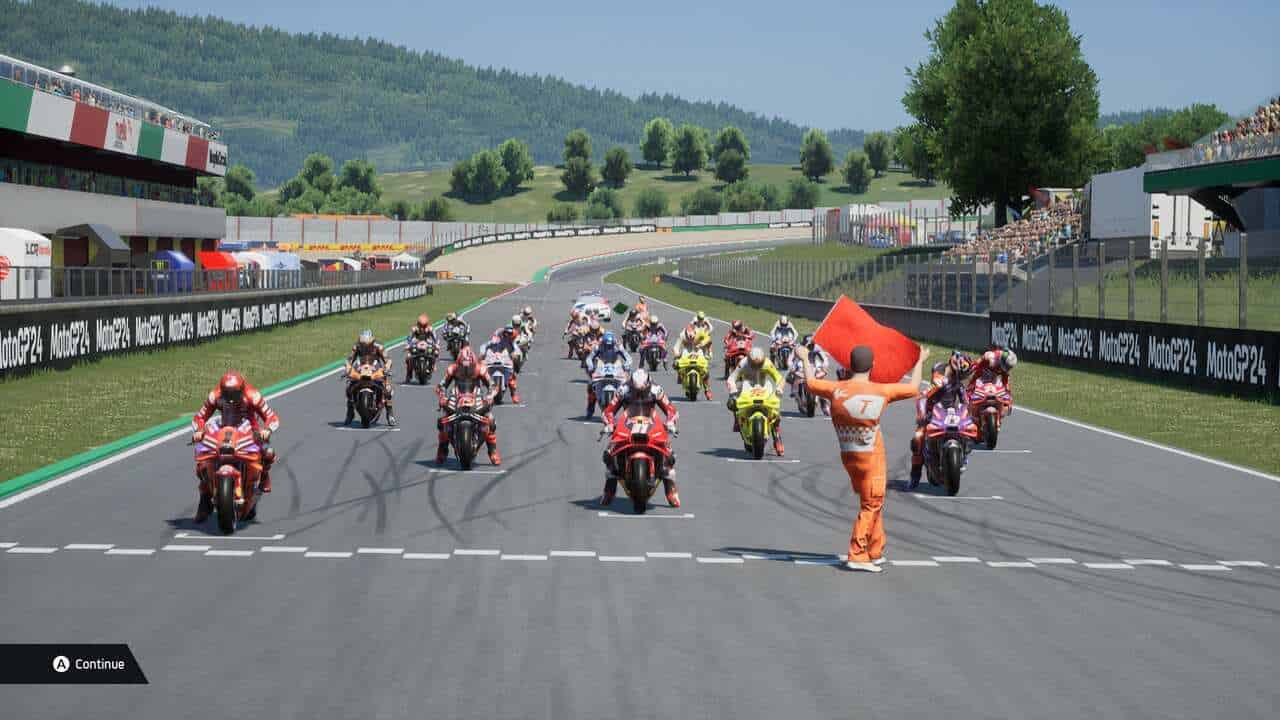 MotoGP 24 review: A man waves a red flag in front of the grid before a race.