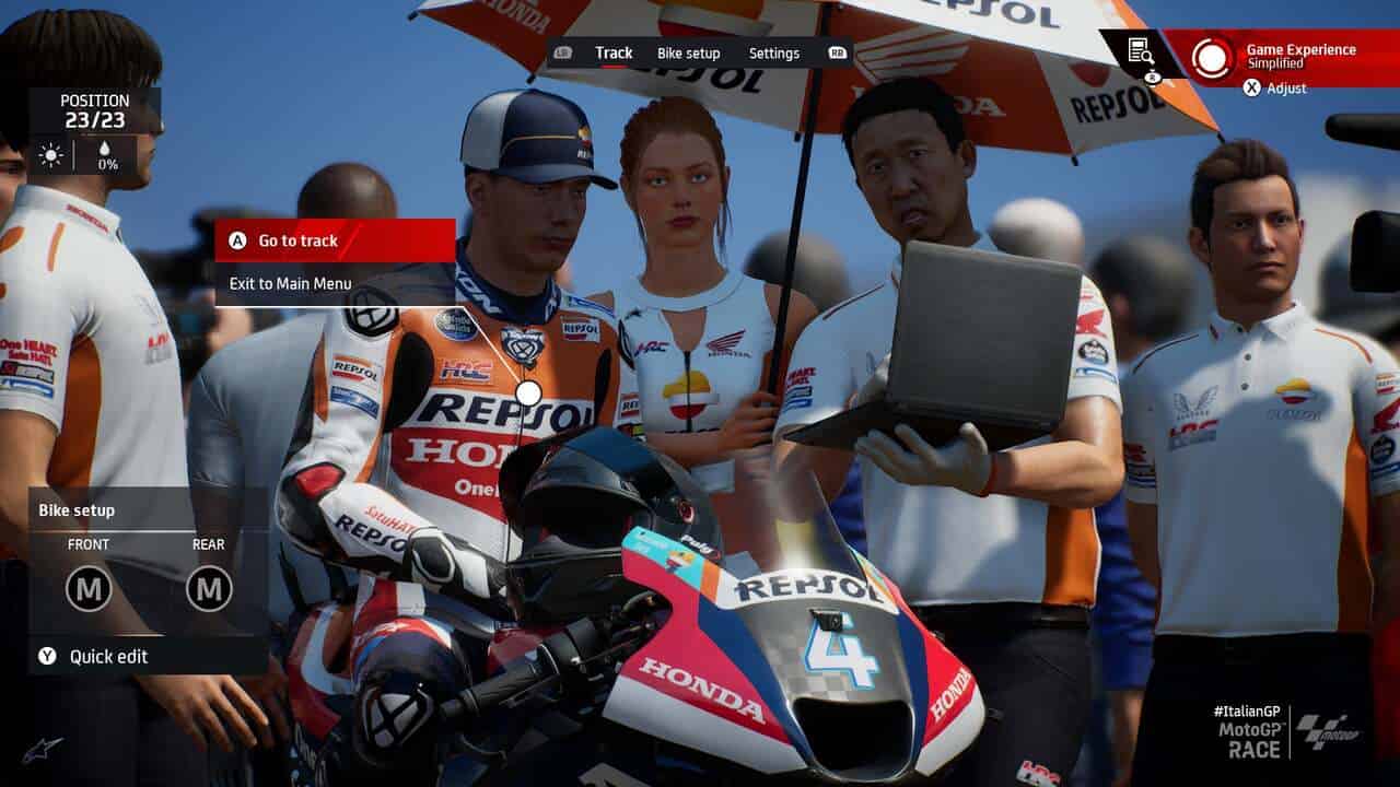 MotoGP 24 review: A rider before a race with a team member showing them something on a laptop.