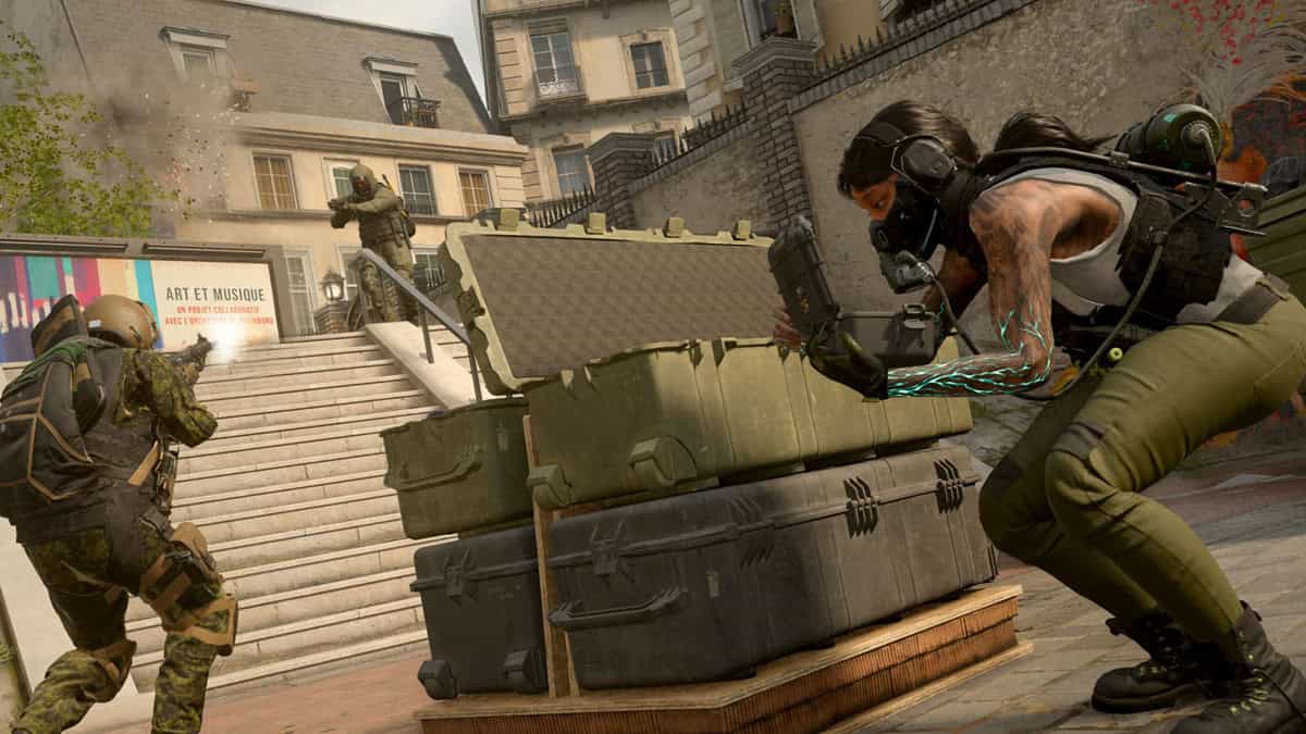 Three players in tactical gear face off as one of them defuses a bomb in the game.