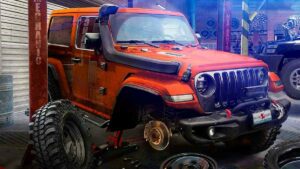 An orange vehicle being worked on in a garage.
