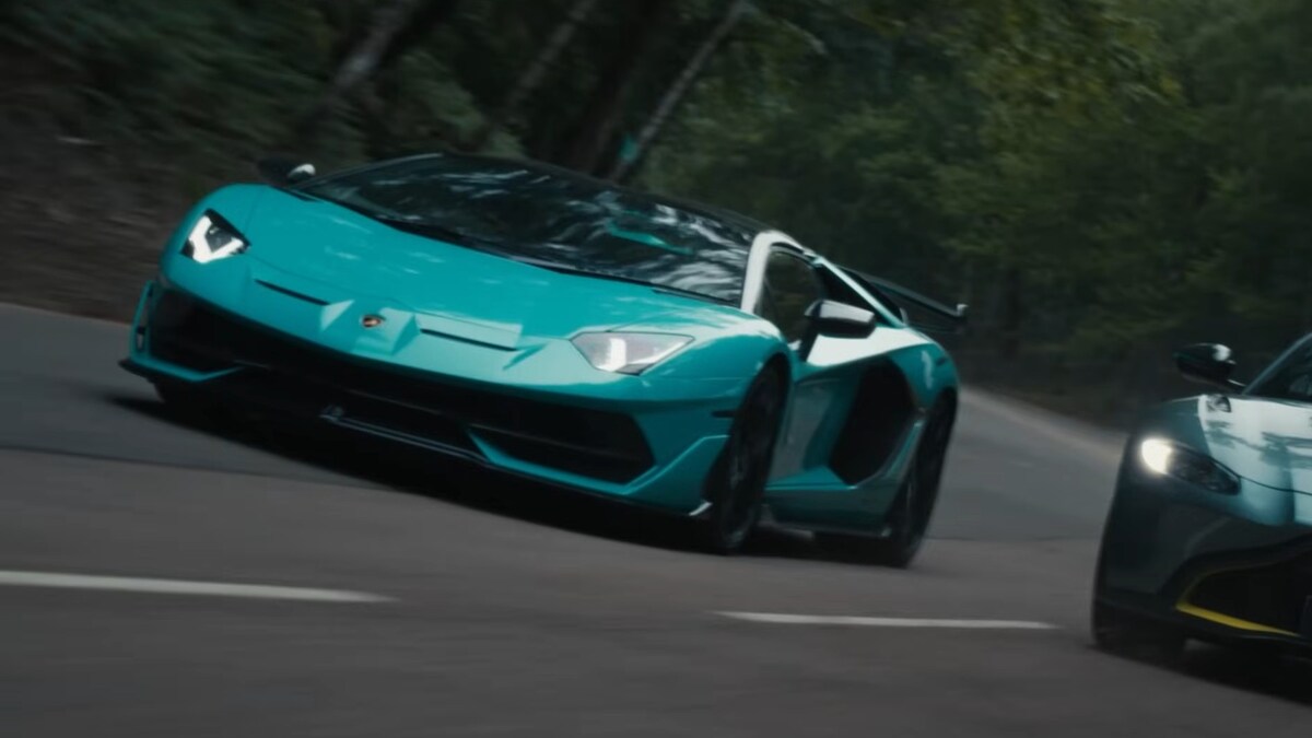 Test Drive Unlimited Solar Crown all cars list: A turquoise car driving down a forested road.