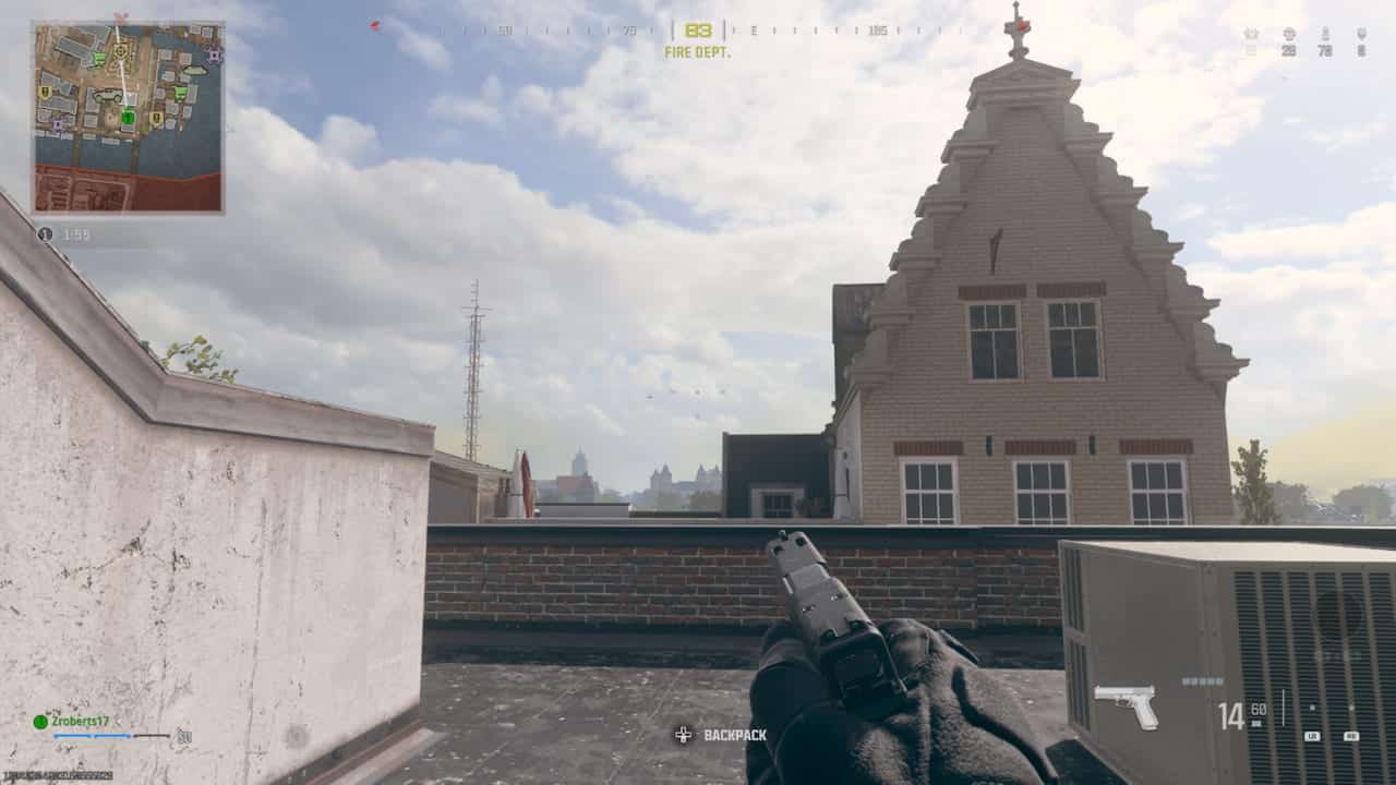 First-person perspective of a player with a handgun on a rooftop in a virtual warzone mobile game environment.