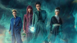 A group of people standing in front of a cloudy sky, eagerly discussing the Yu Yu Hakusho Live Action release date.