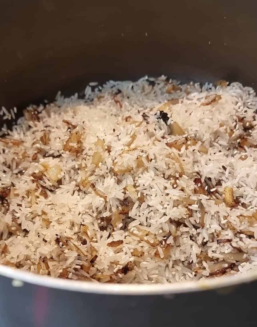 Rice, onions, and garlic mixed together in a pot.