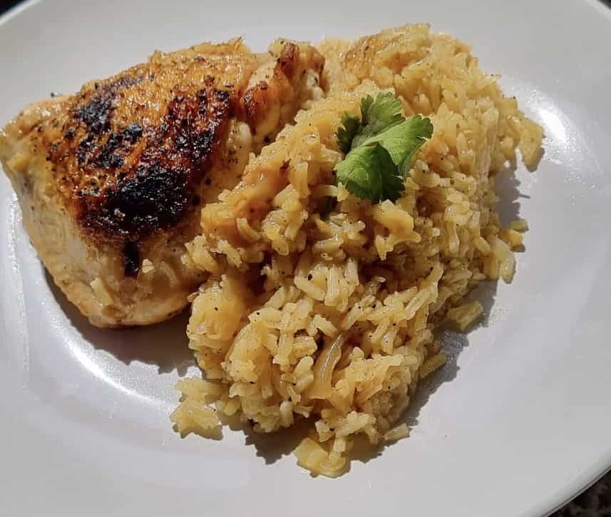 The Prime Poultry Pilaf recipe on a plate: some golden rice and a pan fried chicken thigh.