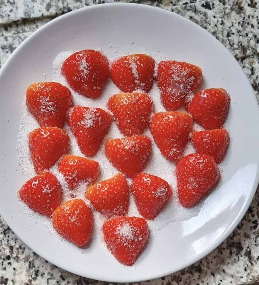 Strawberries on a plate of sugar.